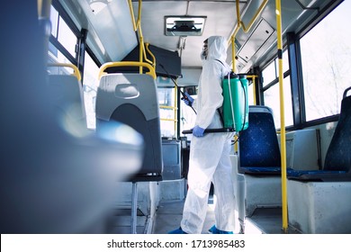 Public transportation healthcare. Man in white protection suit disinfecting and sanitizing handlebars and bus interior to stop spreading highly contagious coronavirus or COVID-19. - Powered by Shutterstock