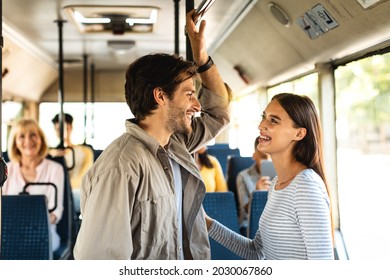 Public Transportaton. Portrait of smiling young woman and man standing at autobus, talking and looking at each other, holding handles, enjoying ride or travel together in crowded vehicle - Powered by Shutterstock