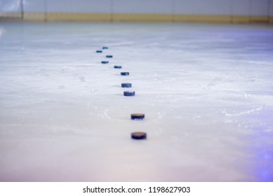 Pucks are organized in a line on the ice.