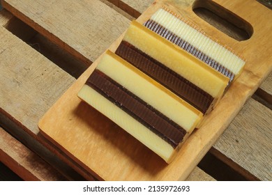 Pudding lapis surabaya layered with different tastes of milk, and mixed with herbs and spices. Chocolate layered pudding on a wooden cutting board. - Shutterstock ID 2135972693