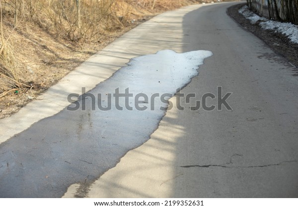 Puddle on asphalt. Wet road. Spilled water on\
pedestrian zone. Big\
puddle.