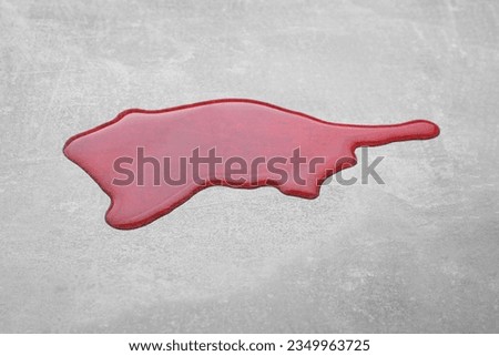 Puddle of red liquid on light grey surface