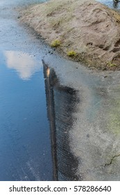 Puddle with silos reflection and sand next to it