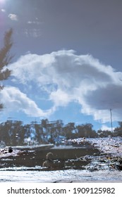 puddle that reflects the sky with clouds