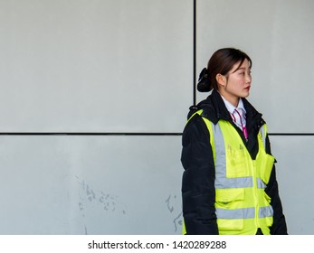 PUDONG, SHANGHAI - 13 MAR 2019 - A Young Asian Chinese Woman Airport Employee In Yellow Vest At Pudong Airport, Shanghai With Copy Space. 