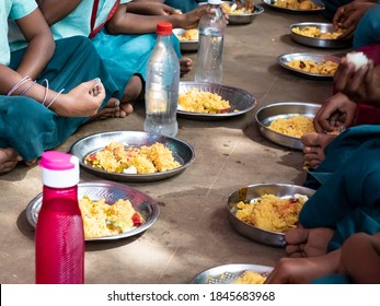 PUDUCHERRY, TAMIL NADU, INDIA - DECEMBER Circa, 2018. Unidentified poor classmates children with uniforms sitting on the floor outdoors, eating with their right hand some rice with masala. Unhealthy 
