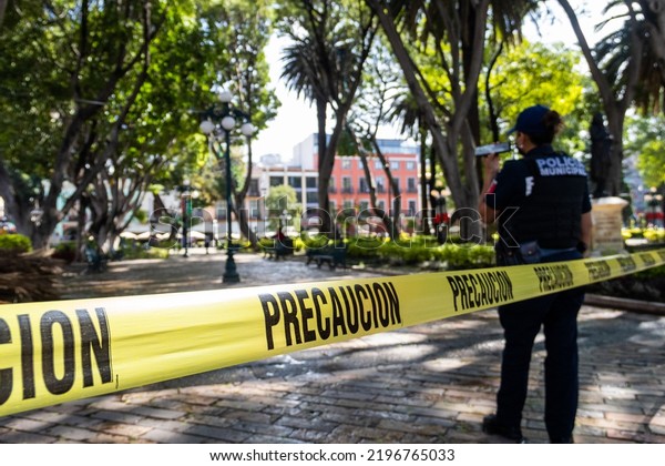 Puebla, Mexico - August 15, 2022:\
Policewoman watches that they do not pass the caution\
tape