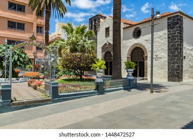 Puerto de la Cruz, Tenerife, Spain - July 10, 2019: Colourful houses and palm trees on streets. People relax and have fun on a warm sunny summer day. Have breakfast, drink coffee in a cozy cafe.
