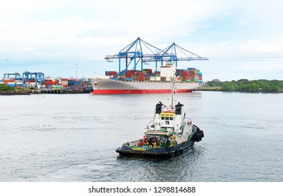 Puerto Quetzal, Guatemala.  Working Tug Boat In Harbour With Container Ship In Background