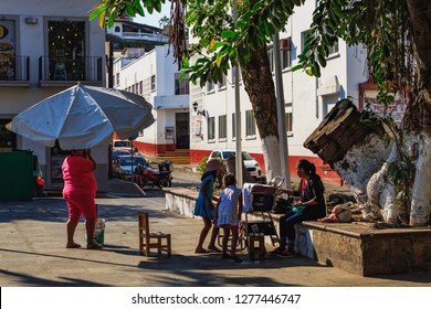 Puerto Vallarta Mexico 04/23/2017 Woman Setting Up Umbrella At Shoeshine Chair In Park At Centro.