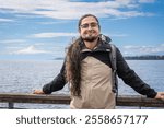 Puerto Varas, Los Lagos, Chile. Young male traveler - tourist beside the snow-capped volcano Osorno and Lake Llanquihue as seen from the city of Puerto Varas in Chilean Patagonia.