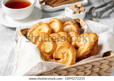 Puff. Flaky sugar Palmiers cookies in a basket on a light background. Sweet homemade cakes