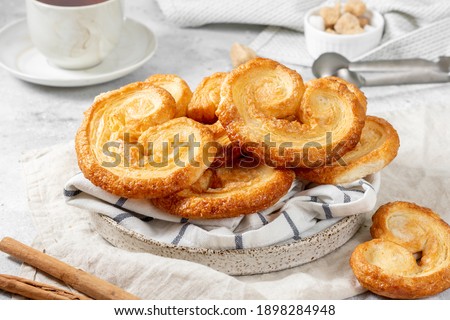 Puff. Flaky sugar Palmiers cookies in a ceramic plate on a light background. Sweet homemade cakes	