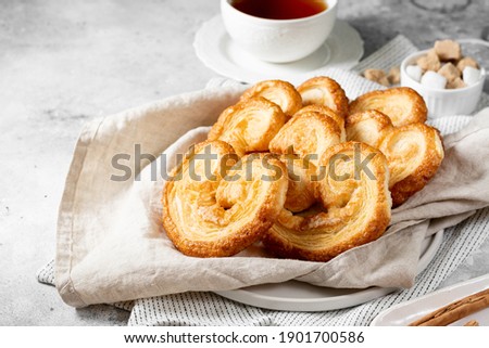 Puff. Flaky sugar Palmiers cookies in a basket on a light background. Sweet homemade cakes	