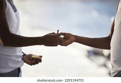Puff, puff, pass. two unrecognisable men smoking a marijuana cigarette.