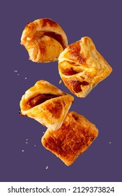 Puff Pastry Buns With Crumbs Flying On Purple Background