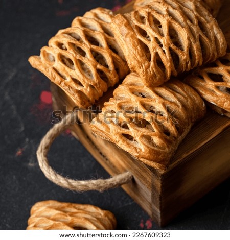 Puff pastry with fruit filling decorated with mesh on top. Baking on wooden bag. Dark background. View from above. Close-up. Soft focus.