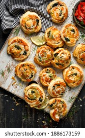 Puff Pastry Pinwheels stuffed with salmon, cheese and spinach served on a board on a black wooden table top view