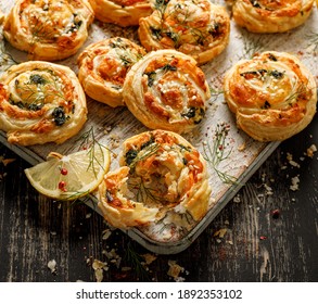 Puff Pastry Pinwheels stuffed with salmon, cheese and spinach on a wooden board top view. Delicious snacks perfect as a party food