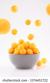puffed ball cheese corn chips in gray bowl and sprinkled isolated on white background