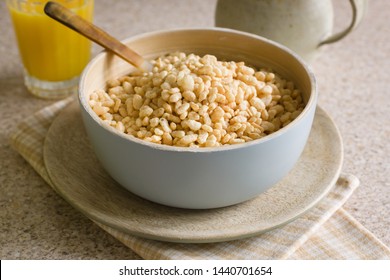 Puffed Rice Breakfast Cereal In A Wooden Bowl With Juice And A Milk Jug