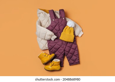 Puffer Jacket, Warm  Pants Hat And Boots On Orange Background. Set Of Baby Clothes For  Winter. Fashion Kids Outfit.