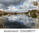 Puffy white and grey storm clouds reflecting on a lake in New Jersey