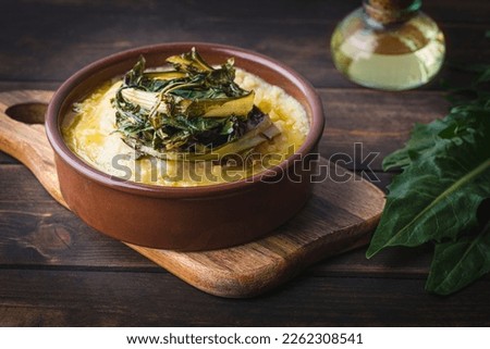 Pugliese recipe   Fave e cicoria:  fava beans or broad beans porridge  with Asparagus chicory, italian dandelion chicory or Catalonian chicory on the wooden  rustic table, tradition poor Bari cuisine 