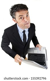 Pugnacious Businessman Holding A Laptop Computer In His Hands Standing Looking Up At The Camera With A Determined Dogmatic Expression, Isolated On White