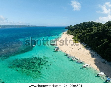 Puka Shell Beach with white sand and boats floating at shoreline. Boracay, Philippines.