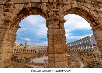 The Pula Amphitheater is a stunning sight at sunset. As the sun sinks low in the sky, the ancient stone structure glows golden, casting long shadows across the grassy field in Pula, Istria, Croatia.