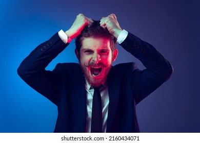 Pull hair on head. Excited young stylish man in business suit shouting isolated on dark blue studio background. Concept of human emotions, facial expression, sales, ad, fashion and beauty