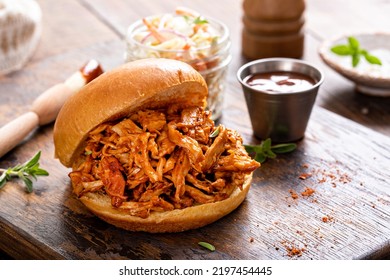 Pulled bbq chicken sandwich on a brioche bun served with cole slaw and bbq sauce - Shutterstock ID 2197454445