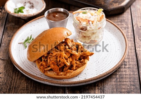 Pulled bbq chicken sandwich on a brioche bun served with cole slaw and bbq sauce