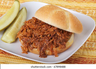Pulled pork barbecue sandwich with pickles on a plate