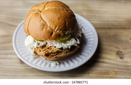 Pulled Pork Barbecue Sandwich With Sweet Pickles And Coleslaw On A White Plate. 