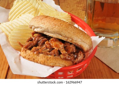 A Pulled Pork Or Beef Sandwich In A Basket With Potato Chips And Beer