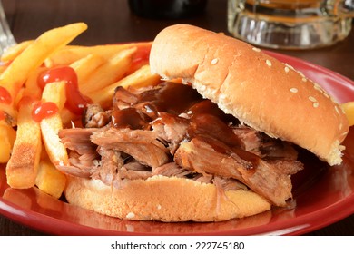 A Pulled Pork Sandwich With Barbecue Sauce, Fries And Beer