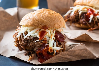 Pulled pork sandwich with cabbage slaw on top served on paper