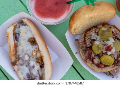 Pulled Pork Sandwich, Preztel Sticks And Chili Dog With Cocktail On Tiki Bar Green Table