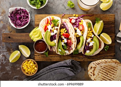 Pulled pork tacos with red cabbage, tomatoes, corn, feta and avocados overhead shot