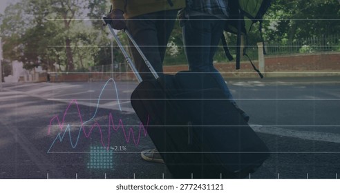 Pulling black suitcase, two men in jeans walking with backpack on tree-lined street, data graphs. Travel, urban, road, luggage, bag, companions, sunny