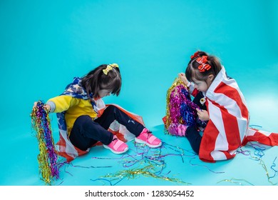Pulling out elements. Attentive little sisters sitting on the floor surrounded with decoration of independence day