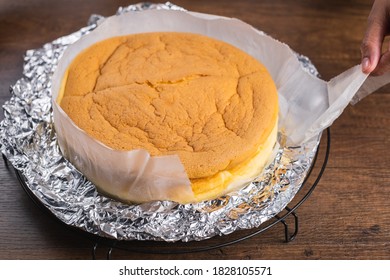 Pulling Out The Paper Linging That Wrap The Cheesecake In The Cake Tin.