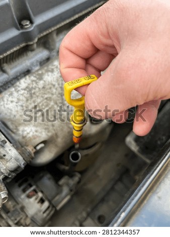 Pulling out yellow car engine oil dipstick close up