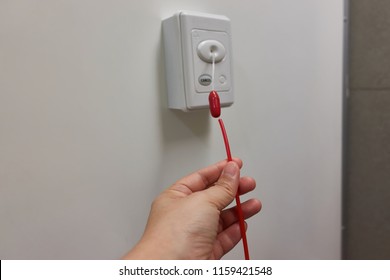 Pulling red emergency call switch for calling nurse to rescue in patient shower room.       
