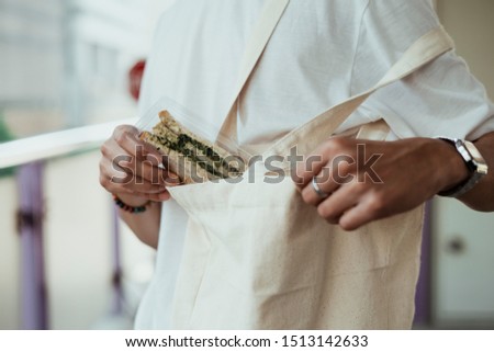 Pulling a sandwich in plastic package out of the cloth bag. 