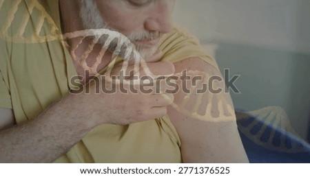 Pulling up sleeve, man touching upper arm patch at clinic with DNA overlay, in yellow T-shirt. Genetics, biotech, deltoid, elderly, healthcare, medical, calm