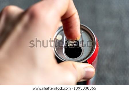 Pulling the tab of a beverage can with a left male hand. Opening a refreshment drink like cola or energydrink after a hard day.