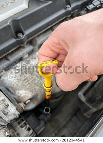 Pulling yellow plastic engine oil dipstick handle close up
